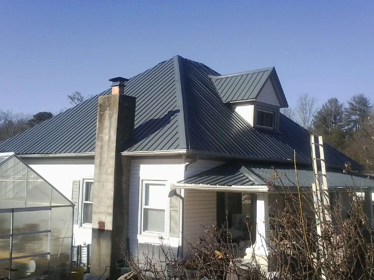 Dark blue standing seam metal roof on a white farmhouse with dormer — Slate & Tile Roof Repair by Roofing Brothers in Beech Island