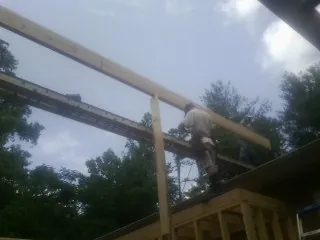 Carpenter setting a ridge beam over a new addition frame — Ice Dam Removal by Roofing Brothers in Beech Island
