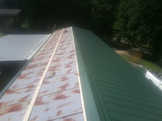 Old rusted panels beside newly installed green metal roofing — Wind Damage Roof Repair by Roofing Brothers in Beech Island