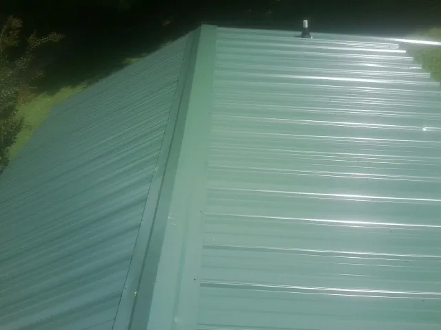 New green metal panels meeting at the ridge of a roof — Flat Roof Repair work by our crew in Beech Island