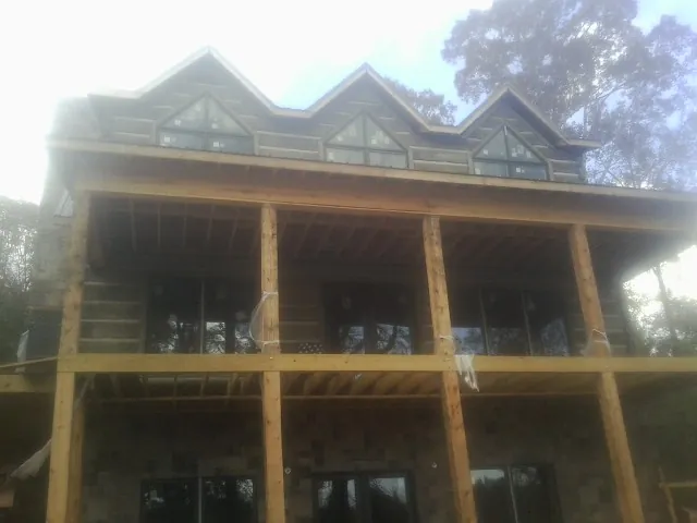 Dormers and porch framing on a large log home under construction — Roof Coating work by our crew in Beech Island