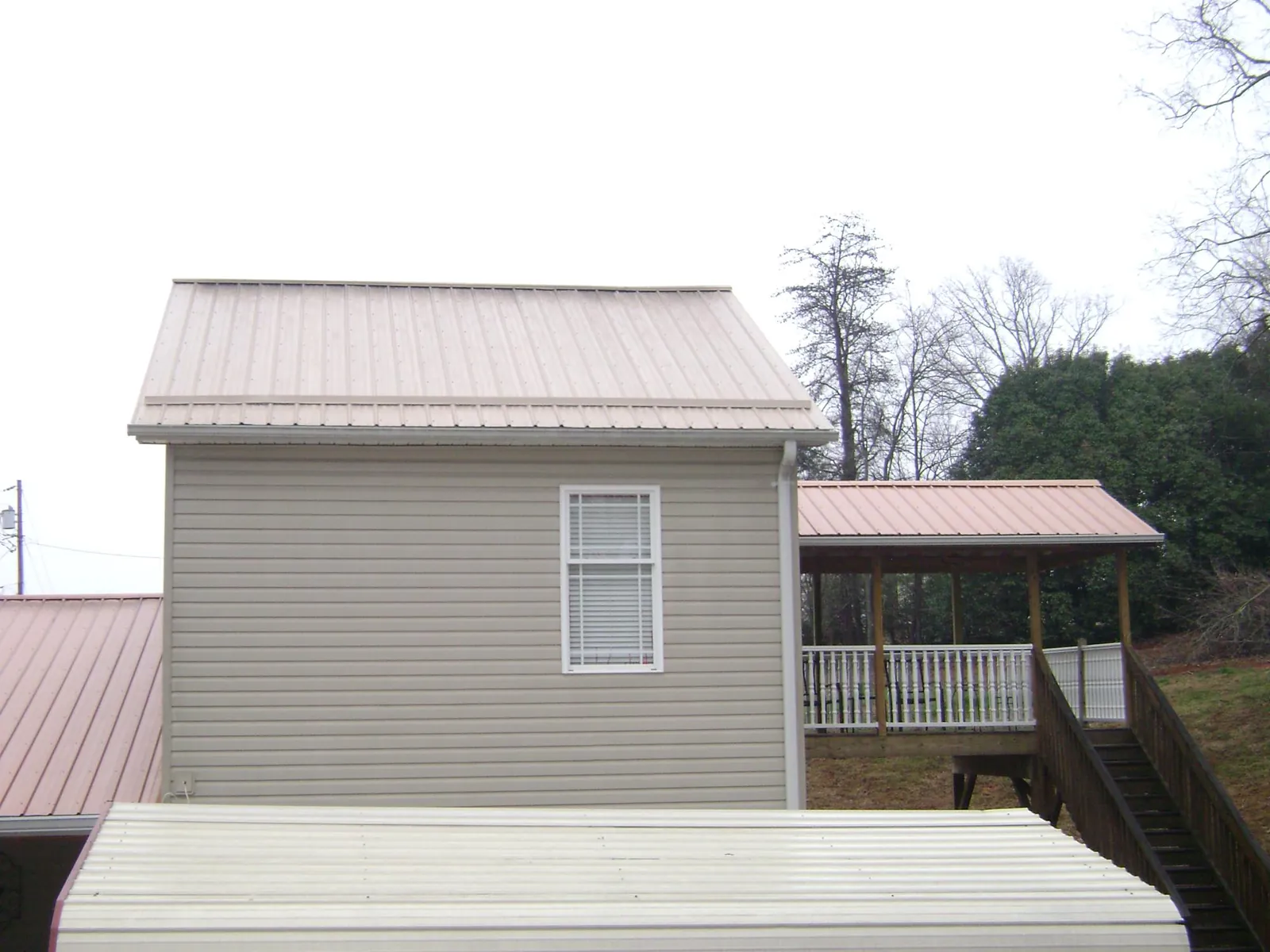 Tan metal roofs on a two story addition and attached porch, from a Roof Replacement job in Beech Island