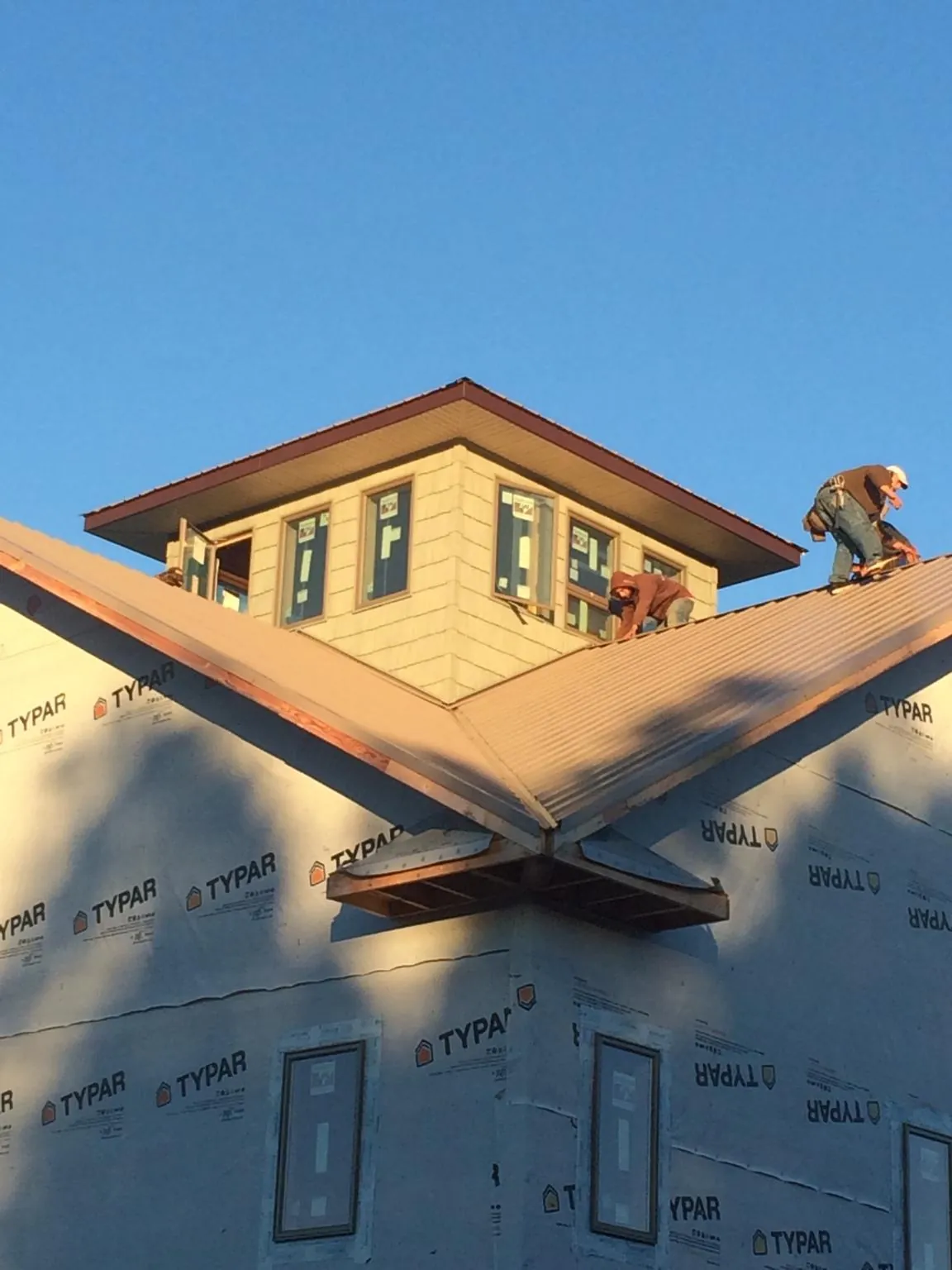 Roofers working around a rooftop cupola on a new metal roof at sunset — Roof Waterproofing in Beech Island by Roofing Brothers